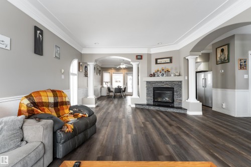 Living area featuring hardwood flooring, a stone fireplace, and decorative columns - 4403 Yeoman Drive, Onoway, AB - Indoor Photo Showing Living Room With Fireplace