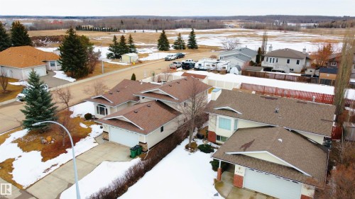 This property features a well-maintained brown shingle roof and a spacious driveway leading to an attached garage - 4403 Yeoman Drive, Onoway, AB - Outdoor With View