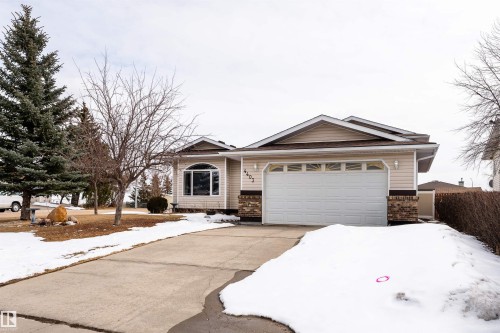 The property features light-colored siding, a white garage door, and stone accents on the facade - 4403 Yeoman Drive, Onoway, AB - Outdoor With Facade