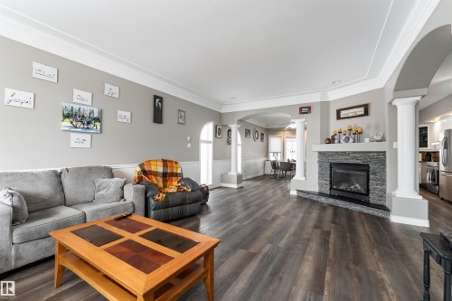 Living room featuring wood-style flooring, a fireplace with a stone surround and mantel, and crown molding - 4403 Yeoman Drive, Onoway, AB - Indoor Photo Showing Living Room With Fireplace