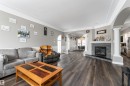 Living room featuring wood-style flooring, a fireplace with a stone surround and mantel, and crown molding - 4403 Yeoman Drive, Onoway, AB  - Indoor Photo Showing Living Room With Fireplace 