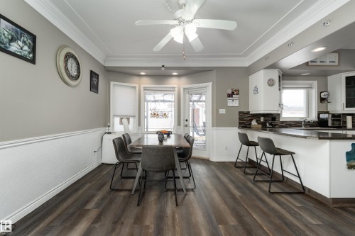 Dining area featuring wood-style flooring, a ceiling fan, and a view of the kitchen area with a peninsula counter and bar seating - 4403 Yeoman Drive, Onoway, AB - Indoor Photo Showing Dining Room