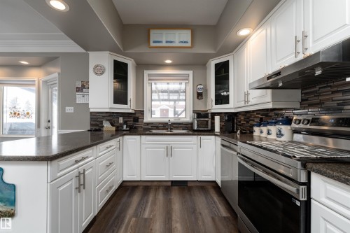 The kitchen features white cabinetry, dark countertops, and stainless steel appliances - 4403 Yeoman Drive, Onoway, AB - Indoor Photo Showing Kitchen