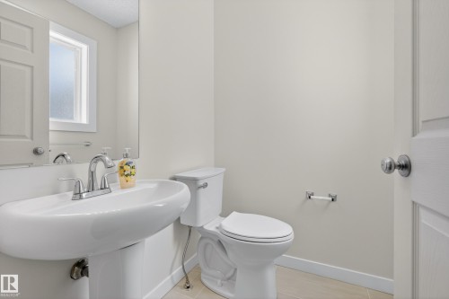 The bathroom features a pedestal sink with a chrome faucet, a toilet, and light-colored walls - 9 10909 106 Street, Edmonton, AB - Indoor Photo Showing Bathroom