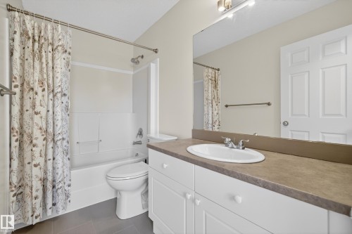 Bathroom featuring a white vanity with an oval sink, a large mirror, and a combination shower and bathtub - 9 10909 106 Street, Edmonton, AB - Indoor Photo Showing Bathroom