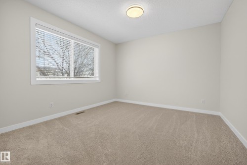 This room features light-colored carpet flooring, a window with blinds, and a ceiling light fixture - 9 10909 106 Street, Edmonton, AB - Indoor Photo Showing Other Room