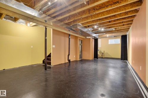Spacious lower level with exposed ceiling joists and ductwork, featuring a window and staircase access - 9 10909 106 Street, Edmonton, AB - Indoor Photo Showing Basement