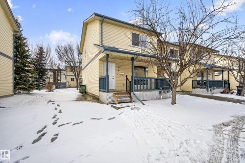 The property features a two-story exterior with light-colored siding and a covered front porch with dark railings - 9 10909 106 Street, Edmonton, AB - Outdoor