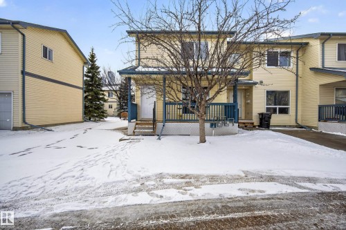 The property features a two-story exterior with light-colored siding, a front porch, and a driveway - 9 10909 106 Street, Edmonton, AB - Outdoor