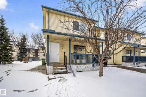 The property features yellow siding, a front porch with a dark railing, and a white front door - 9 10909 106 Street, Edmonton, AB - Outdoor