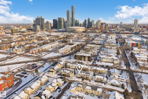 This aerial view showcases the property within a vibrant urban neighborhood, featuring a prominent downtown skyline in the background - 9 10909 106 Street, Edmonton, AB - Outdoor With View