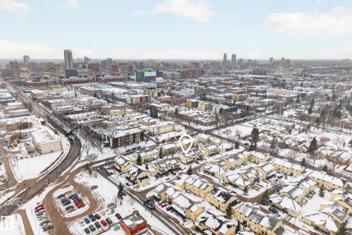 Aerial view showcasing the property's location within a developed neighborhood, featuring surrounding buildings and a distant city skyline - 9 10909 106 Street, Edmonton, AB - Outdoor With View