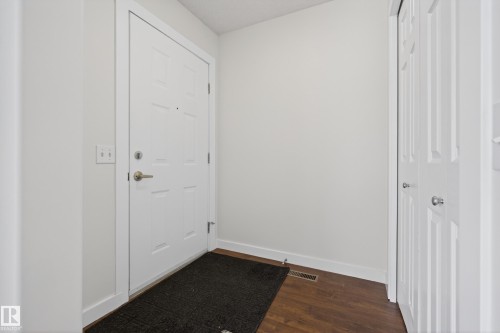 Entryway featuring a white paneled door with brushed nickel hardware, light-colored walls, and dark wood flooring - 9 10909 106 Street, Edmonton, AB - Indoor Photo Showing Other Room