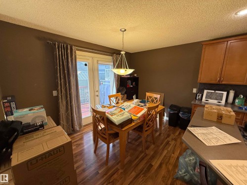 Dining area featuring wood-look flooring, a chandelier, and double doors opening to an exterior space - 21113 92A Avenue, Edmonton, AB - Indoor Photo Showing Dining Room