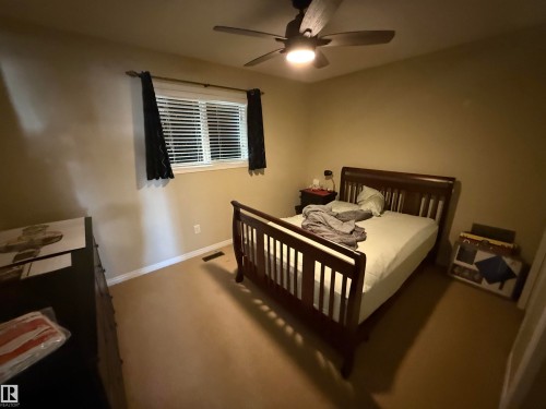 This room features a window with blinds and dark curtains, a ceiling fan with integrated lighting, and carpeted flooring - 21113 92A Avenue, Edmonton, AB - Indoor Photo Showing Bedroom