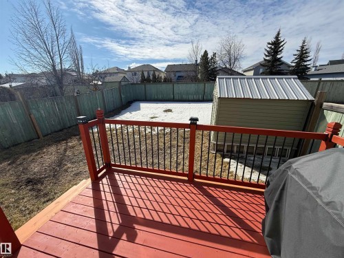 The property features a red wood deck with black metal railings, overlooking a fenced backyard with a shed - 21113 92A Avenue, Edmonton, AB - Outdoor