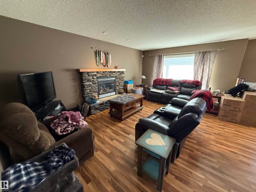 The living area features hardwood floors, a stone fireplace with a wooden mantel, and a window with blinds and curtains - 21113 92A Avenue, Edmonton, AB - Indoor Photo Showing Living Room With Fireplace
