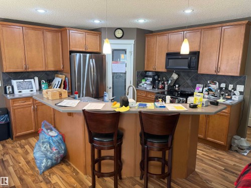The kitchen features light wood cabinetry, a dark tiled backsplash, and stainless steel appliances - 21113 92A Avenue, Edmonton, AB - Indoor Photo Showing Kitchen