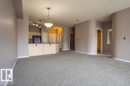 Spacious open-concept living area with light-colored carpeting and pale lavender walls - 326 4304 139 Ave, Edmonton, AB - Indoor Photo Showing Kitchen
