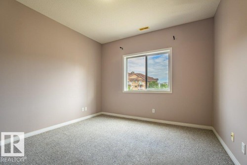 The property features wall-to-wall carpeting, a window providing natural light, and neutral-toned walls - 326 4304 139 Ave, Edmonton, AB - Indoor Photo Showing Other Room