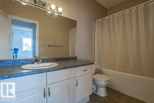 Bathroom featuring a vanity with a sink, a large mirror, and a shower with a shower curtain - 326 4304 139 Ave, Edmonton, AB - Indoor Photo Showing Bathroom