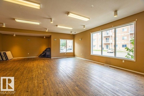 Spacious room featuring wood-style flooring, large windows, and overhead lighting - 326 4304 139 Ave, Edmonton, AB - Indoor Photo Showing Other Room
