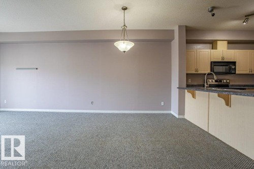 The property features a kitchen with light-colored cabinetry, a dark countertop, and a stainless steel sink with a faucet - 326 4304 139 Ave, Edmonton, AB - Indoor Photo Showing Kitchen With Double Sink