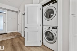 The property includes a stacked washer and dryer unit, and light wood flooring - 