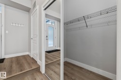The property entrance features wood flooring, a white door with frosted glass, and a coat rack on a light gray wall - 