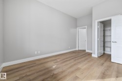 This room features light-colored laminate flooring, neutral wall paint, and white trim - 