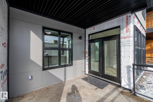 The property features a patio area with concrete flooring, a black metal ceiling, and grey exterior paneling - 114 10531 117 Street, Edmonton, AB - Outdoor With Exterior