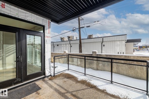 Property with a balcony featuring a glass and metal railing, concrete flooring, and double doors with glass panels - 114 10531 117 Street, Edmonton, AB - Outdoor With Exterior