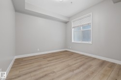 This room features light-toned wood flooring, light grey walls, and a window with blinds providing natural light - 