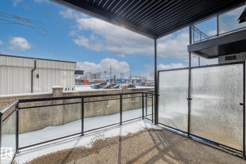 The private balcony features a concrete floor and modern glass railings with black metal frames - 114 10531 117 Street, Edmonton, AB - Outdoor With Exterior