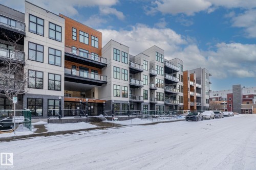 The property features a multi-story building with a modern architectural style, incorporating light-colored panels, dark window frames, and wood-toned accents - 114 10531 117 Street, Edmonton, AB - Outdoor With Facade