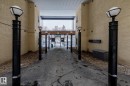 The property features a gated entrance with black lampposts, a concrete pathway, and textured beige exterior walls - 114 10531 117 Street, Edmonton, AB  -  With Exterior 
