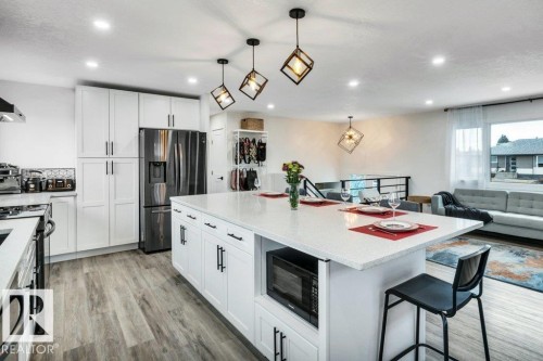 Modern kitchen featuring white cabinetry, a large island with a light-colored countertop, and recessed lighting - 6719 94B Avenue, Edmonton, AB - Indoor Photo Showing Other Room