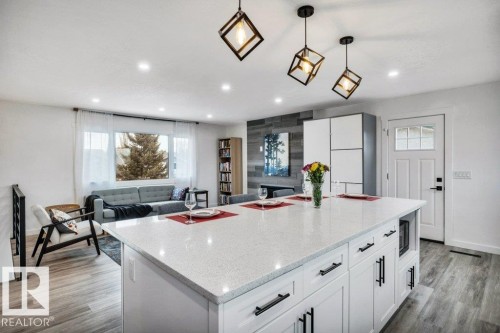 Spacious open-concept living area featuring an expansive kitchen island with a light-colored countertop, recessed lighting, and stylish pendant lights - 6719 94B Avenue, Edmonton, AB - Indoor