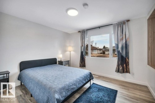 This bedroom features light wood-style flooring, a window offering exterior views, and a ceiling light fixture - 6719 94B Avenue, Edmonton, AB - Indoor Photo Showing Bedroom