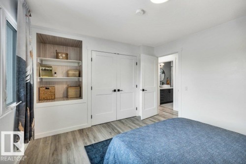 This room features light-toned flooring, built-in shelving, and white doors with dark hardware - 6719 94B Avenue, Edmonton, AB - Indoor Photo Showing Bedroom