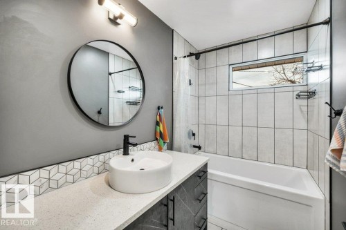 Bathroom featuring a vanity with a vessel sink, a round mirror, and a tiled shower with a window - 6719 94B Avenue, Edmonton, AB - Indoor Photo Showing Bathroom