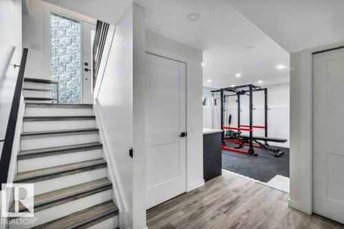 Finished lower level featuring stairs with wooden treads and white risers, and a recreation area with wood-look flooring and recessed lighting - 6719 94B Avenue, Edmonton, AB - Indoor Photo Showing Other Room