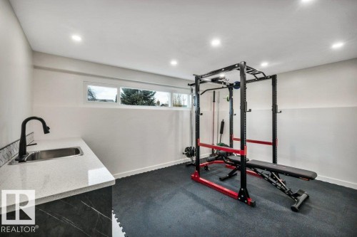 This versatile room features white walls, recessed lighting, and a window providing natural light - 6719 94B Avenue, Edmonton, AB - Indoor Photo Showing Gym Room