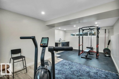 The property features a dedicated fitness area with recessed lighting, light-colored walls, and a combination of wood-look flooring and dark floor mats - 6719 94B Avenue, Edmonton, AB - Indoor Photo Showing Gym Room