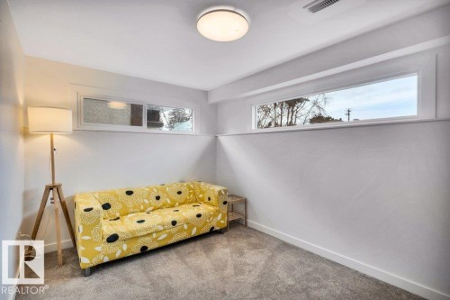This versatile room features neutral white walls, grey carpet, and two transom windows that provide natural light - 6719 94B Avenue, Edmonton, AB - Indoor