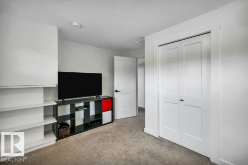 This room features a neutral carpeted floor, built-in shelving, white walls, and a closet with bifold doors - 6719 94B Avenue, Edmonton, AB - Indoor