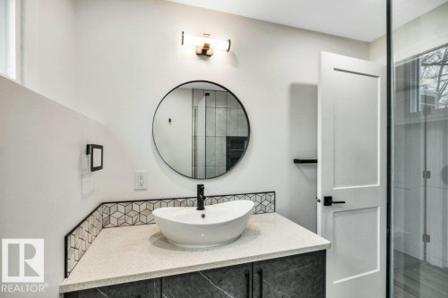 Modern vanity with a vessel sink, a matte black faucet, and a round mirror - 6719 94B Avenue, Edmonton, AB - Indoor Photo Showing Bathroom