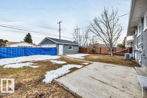 The property features an extensive yard with a concrete patio and a detached garage with two garage doors - 6719 94B Avenue, Edmonton, AB - Outdoor