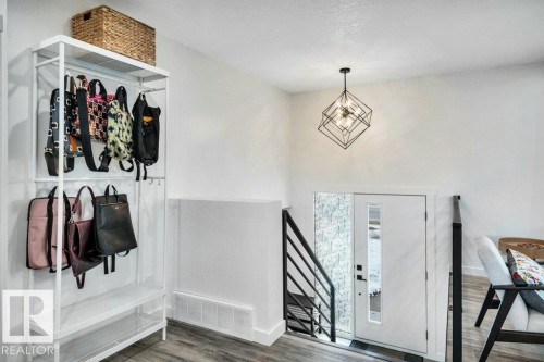 The entryway features a modern geometric pendant light, white walls, and wood-look flooring - 6719 94B Avenue, Edmonton, AB - Indoor Photo Showing Other Room