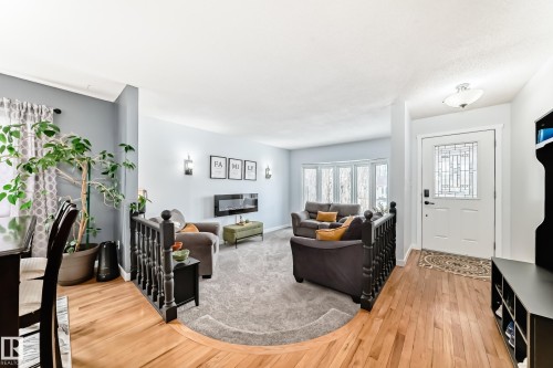 This inviting living space features light blue walls, a modern electric fireplace, and a bay window providing ample natural light - 17819 91A Street, Edmonton, AB - Indoor With Fireplace